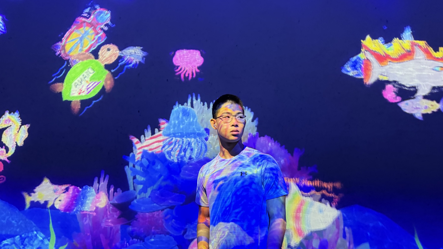 Housen Chen standing in front of a colorful underwater projection
